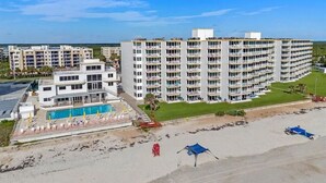 A multi-story hotel with a pool and beach area. - Amazing Direct Oceanfront Condo. Steps to the Bch and Heated Pool. Gated complex (New Smyrna Beach)