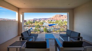Un balcon avec deux canapés et une table, donnant sur une piscine et des montagnes.