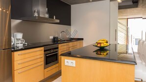 A modern kitchen with a central island, stainless steel appliances, and a view of the outside.