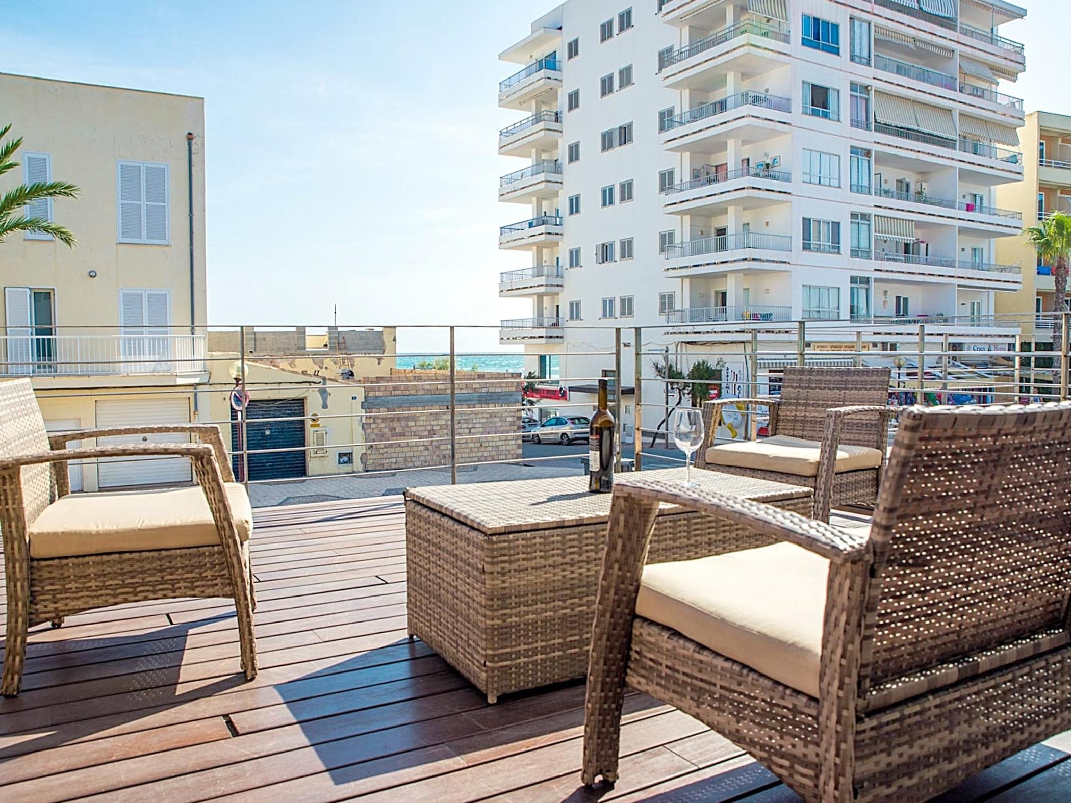 Uma varanda com mobiliário de vime e vista para um edifício alto.