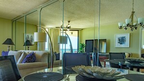 A modern living room with a glass coffee table, a sofa, a TV, and a chandelier. -  Stunning Beachfront View Condo (Orange Beach)
