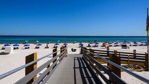 A beach with a wooden walkway leading to the shore, featuring a metal railing and a clear view of the ocean. -  Stunning Beachfront View Condo (Orange Beach)