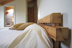A bedroom with a wooden headboard, a bed with white linens, and a door leading to another room. - Agriturismo All' Albaro (Salizzole)