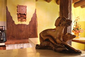 A wooden sculpture of a dog on a table in a room with a wooden ceiling and a clock on the wall. - Agriturismo All' Albaro (Salizzole)