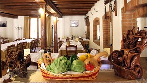 A dining area with wooden tables, chairs, and a basket of fresh produce.