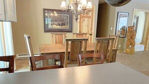 A dining area with a long table and chairs, a chandelier, and framed pictures on the wall. - Keystone Crossing (Keystone)