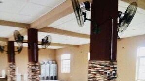 A spacious room with multiple ceiling fans, a large window, and a tiled floor. - Momak 4 Hotel & Suites (Ibadan)
