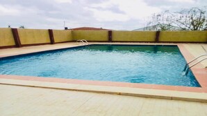 A rectangular swimming pool with a metal ladder on one side, surrounded by a low brick wall. - Momak 4 Hotel & Suites (Ibadan)