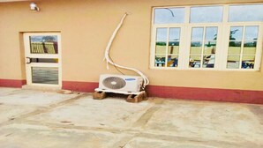 A building with a beige exterior, a window with multiple panes, and a fan on a wooden pallet. - Momak 4 Hotel & Suites (Ibadan)