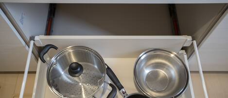 A kitchen drawer with three stainless steel pots and pans.