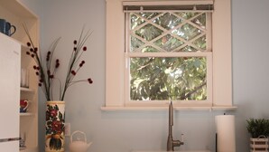 A kitchen with a window, a vase with flowers, a kettle, and a sink. - Mimi's Downtown Cottage (Lodi)