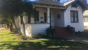 A white house with a porch, a number 302 sign, and a wreath on the door. - Mimi's Downtown Cottage (Lodi)