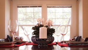 A dining table with a candle centerpiece, two wine glasses, and a bowl of flowers. - Mimi's Downtown Cottage (Lodi)