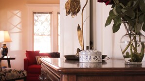 A wooden dresser with a vase of red roses, a decorative lamp, and a mirror. - Mimi's Downtown Cottage (Lodi)