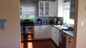 A compact kitchen with white cabinets, a built-in oven, and a sink.