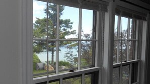 A room with large windows offering a view of a lake and trees.