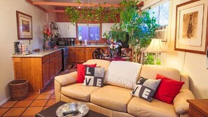A cozy living room with a beige sofa, a coffee table, and a kitchen in the background.