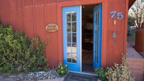 A red building with a blue door, a sign reading "Sedona Serenity", and the number 75 on the wall.