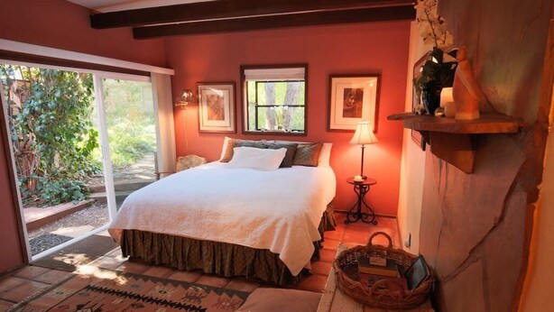 A bedroom with a bed, a window, a lamp, and a shelf with decorative items.