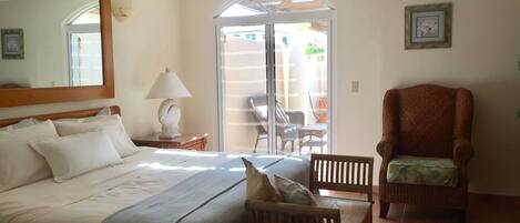 A bedroom with a bed, a chair, a lamp, and a ceiling fan.