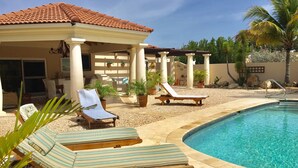 Un espace piscine avec des chaises longues et un coin salon abrité.