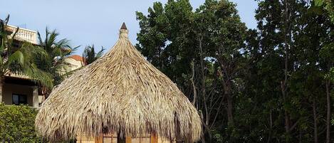 A pool area with a thatched-roof hut, lounge chairs, and a tiled deck.