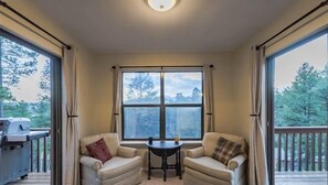 A cozy room with two sofas facing a large window, a small table, and a grill outside. - High Breeze: 'It's a Breeze to getaway' & Pet Friendly. (Ruidoso)