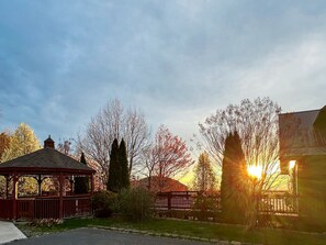 Un kiosque doté d’un toit et de côtés ouverts, entouré d’arbres et d’une clôture.
