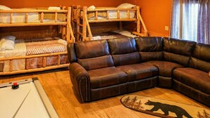 Ein Zimmer mit Etagenbetten, einem Ledersofa und einem Teppich mit Bärenmotiv.