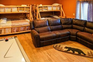 Une chambre avec des lits superposés, un canapé en cuir et un tapis à motifs d’ours.