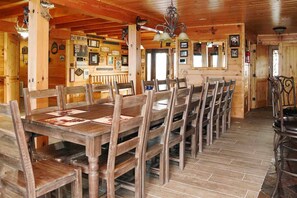 Un coin repas en bois, avec une longue table et des chaises, des tableaux encadrés aux murs et un plafond rustique.
