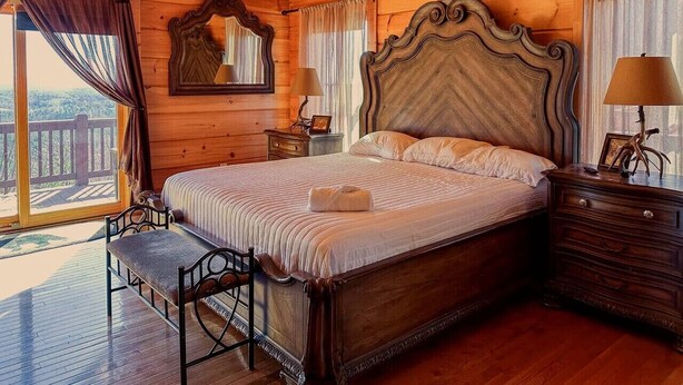 Ein Schlafzimmer aus Holz mit einem großen Bett, einem Nachttisch, einer Kommode, einer Bank und einem Deckenventilator.