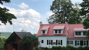 Ein großes, zweistöckiges Haus mit rotem Dach und weißer Fassade, umgeben von einem gepflegten Rasen.