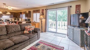 Sala de estar con sofá, televisión y área de cocina con armarios y electrodomésticos.