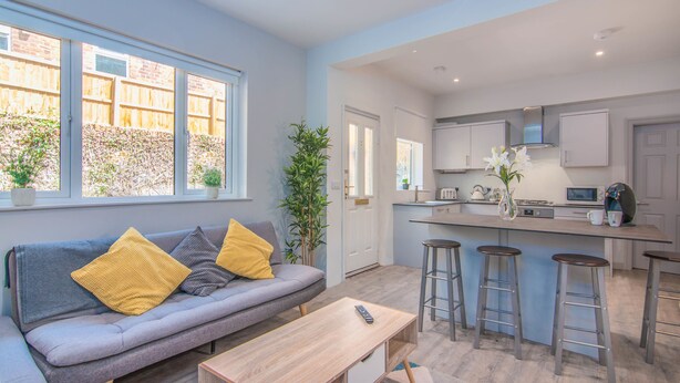 A modern kitchen with a central island, bar stools, and a built-in microwave. - Eden Lodge (High Wycombe)