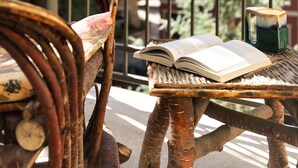 A wicker chair with a book on it, a small table, and a railing with a view of buildings and greenery. - Montaneros 408 - 3 Bedroom Platinum (Vail)