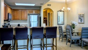 Una cocina moderna con comedor, que incluye una barra con sillas, una mesa de comedor con sillas y un ventilador de techo.