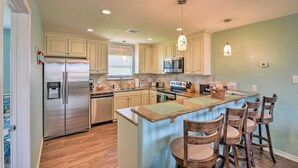 A kitchen with a central island, bar stools, stainless steel appliances, and light-colored cabinetry. - Beautiful newer beach house with spectacular ocean views and right at the beach! (Surfside Beach)