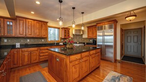 A spacious kitchen with wooden cabinets, a large island, stainless steel appliances, and pendant lighting. - Scenic Mountaintop Chalet w/ Hot Tub & Fire Pit (McHenry)