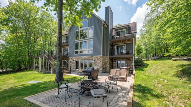 A two-story house with a patio area featuring outdoor furniture and a fire pit. - Scenic Mountaintop Chalet w/ Hot Tub & Fire Pit (McHenry)