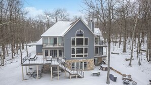 A two-story house with a balcony, stone foundation, and a covered patio area. - Scenic Mountaintop Chalet w/ Hot Tub & Fire Pit (McHenry)
