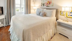A bedroom with a large bed, a TV, a bedside table with a lamp, and a window with curtains. - PERFECT LOCATION 3 Blocks to Sand, Sun, and Folly Fun "Park car and Forget It!" (Folly Beach)