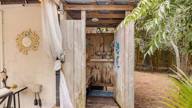 A wooden structure with a bench and a small table, a wooden door, and a wall-mounted light fixture. - PERFECT LOCATION 3 Blocks to Sand, Sun, and Folly Fun "Park car and Forget It!" (Folly Beach)