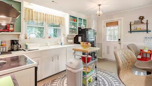 A kitchen with white cabinets, a black refrigerator, a coffee maker, and a small dining area with a chair and table. - PERFECT LOCATION 3 Blocks to Sand, Sun, and Folly Fun "Park car and Forget It!" (Folly Beach)