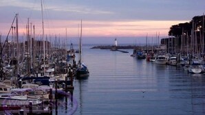 A marina with numerous boats docked, a lighthouse in the distance, and calm water. - Clean, Newly Remodeled Home Steps to  Beach, HOT TUB, LARGE deck  w/ocean peek (Santa Cruz)