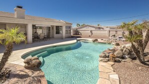 A swimming pool with a curved edge, surrounded by rocks and palm trees. -  Executive style pool home with easy boat parking, Small dogs OK. (Lake Havasu City)