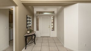 A hallway with a white door, a small table with a vase, and a wall-mounted mirror. -  Executive style pool home with easy boat parking, Small dogs OK. (Lake Havasu City)