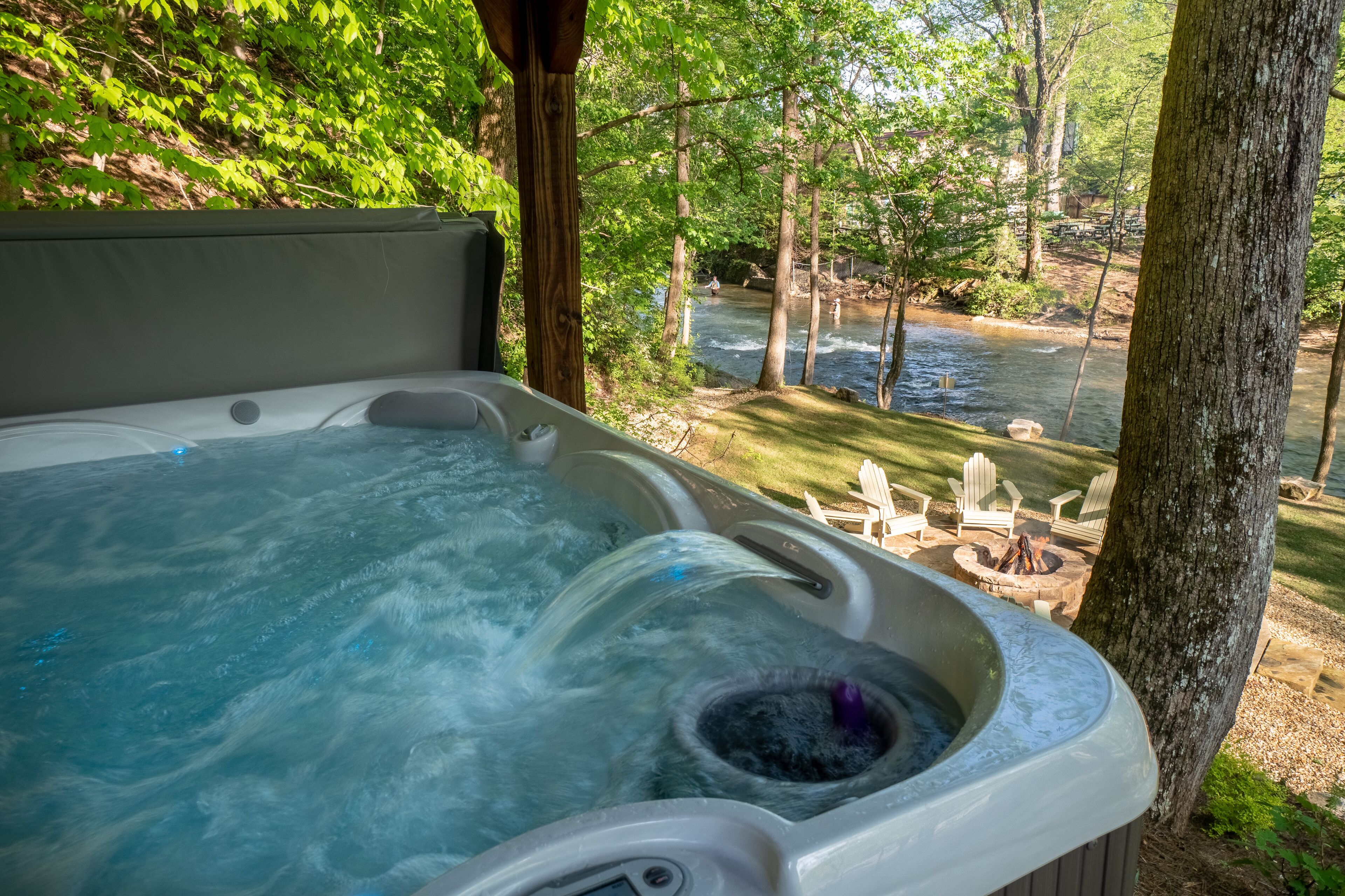 A hot tub with a view of a river and outdoor seating.