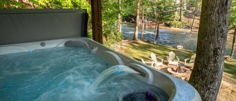 A hot tub with a view of a river and outdoor seating.