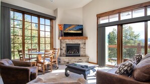Una sala de estar con chimenea de piedra, televisor de pantalla plana y comedor con mobiliario de madera.